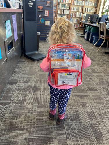 A toddler with back facing and a clear bookbag
